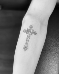 a small cross tattoo on the left arm