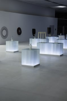 an empty room with white lights on the tables and vases in the center area