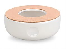 a white bowl with a cork top on a white surface and an orange circle in the center