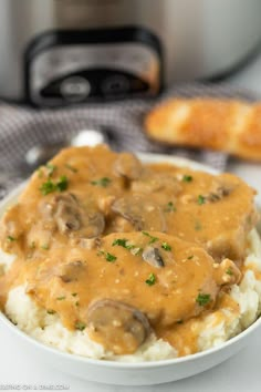 a white bowl filled with mashed potatoes covered in mushroom gravy next to an instant pressure cooker