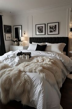 a bed with white comforter and pillows in a bedroom next to two pictures on the wall