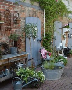 an outdoor garden with lots of potted plants and pots on the side of it