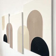 three abstract paintings on a wall with white walls and black, beige, and grey circles