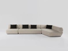 a large sectional sofa with black and white pillows on the back, in front of a gray background