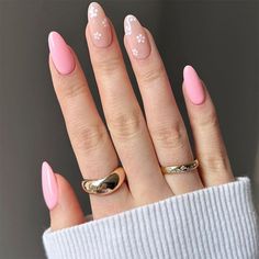 a woman's hand with pink and white nail polish on her nails, holding a gold ring