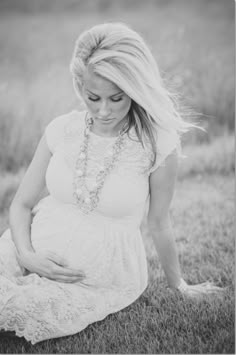 a pregnant woman sitting in the grass