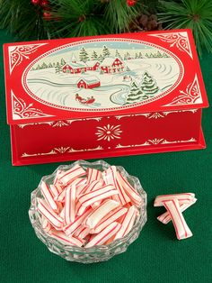 candy canes are in a bowl next to a box