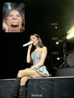 a woman sitting on top of a stage singing into a microphone