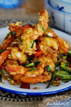 fried food on a plate with chopsticks next to it and a bowl in the background