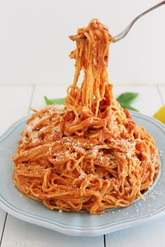 spaghetti being lifted from a blue plate