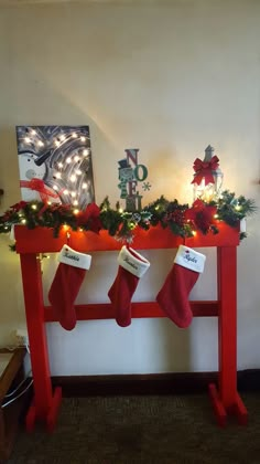 two stockings are hanging on a red table with christmas decorations and lights around them,