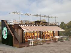 the exterior of a starbucks coffee shop with tables and umbrellas over it's roof