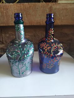 two colorful vases sitting on top of a white table next to eachother