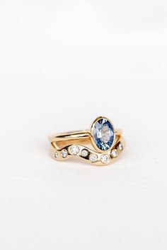 two gold rings with blue topaz and white diamonds on the sides, set against a white background