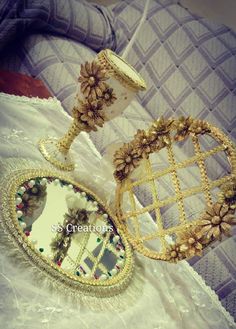 two pieces of jewelry sitting on top of a white cloth covered table next to a mirror