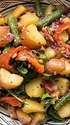 a blue and white bowl filled with potatoes, green beans, and other veggies