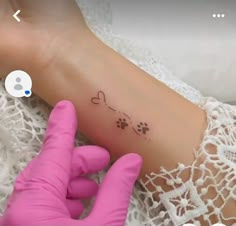 a person with gloves on holding up a small tattoo