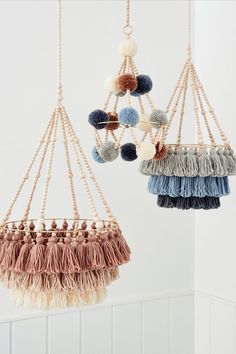 two hanging baskets with tassels and pom - poms