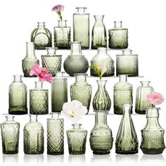 a collection of green glass vases with pink flowers in the middle and white background