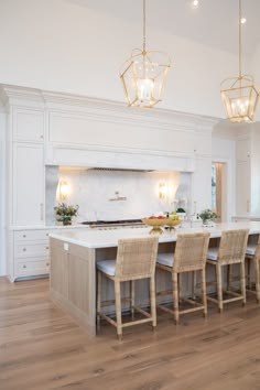 a large kitchen with white cabinets and wooden flooring, along with an island in the middle