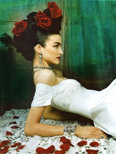 a woman laying on top of a bed with red roses in it's hair