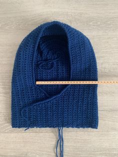 a blue knitted hat with a measuring tape next to it