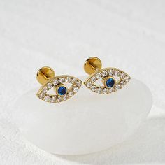 two gold earrings with blue and white stones on top of a rock in the snow