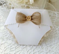 a card with a wooden bow on it and some lace around the edge, sitting on a doily