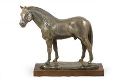 a bronze statue of a horse standing on top of a wooden base with a white background