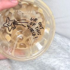 a person holding a plastic cup with writing on it