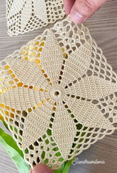 two crocheted doily pieces being held by someone's hand on a table