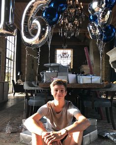 a young man sitting on the floor in front of balloons