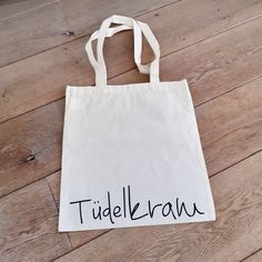 a white bag with the word tidelkrawn written on it sitting on a wooden floor