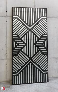 a black and white wall hanging on the side of a cement wall with an abstract design