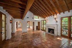 an empty living room with brick flooring and wood beams on the ceiling is shown