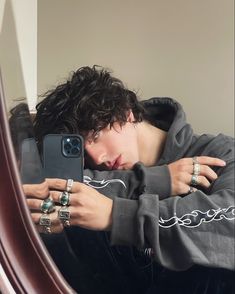 a young man taking a selfie in front of a mirror with his cell phone