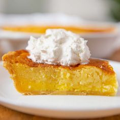 a piece of pie with whipped cream on top sits on a white plate next to another dish