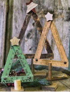 two wooden christmas trees with rulers and stars on them, one has a tape measure in the shape of a triangle