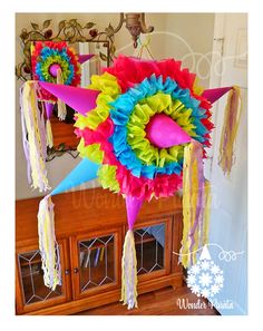 a colorful kite hanging from the ceiling with tassels on it's sides