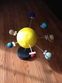 a yellow ball with pins stuck to it sitting on top of a wooden table