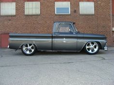 an older pickup truck parked in front of a brick building