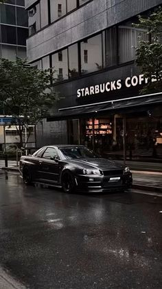 a black car is parked on the side of the street in front of a starbucks