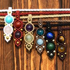 several bracelets are hanging on a wooden wall with beads and other items attached to them