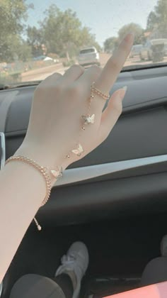 a woman's hand holding onto the steering wheel of a car while wearing a bracelet