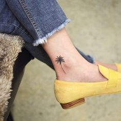 a small palm tree tattoo on the left side of her foot, which is attached to a pair of yellow shoes