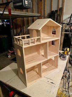 a wooden doll house sitting on top of a workbench in a garage with tools nearby