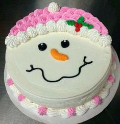 a cake decorated like a snowman with pink frosting on it's face