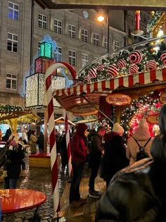 many people are walking around in the city with christmas decorations and candy canes on display