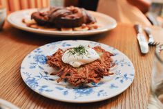 two plates filled with food sitting on top of a wooden table next to silverware