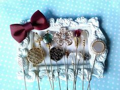 there are many pins and brooches on the white tray with blue polka dot wallpaper